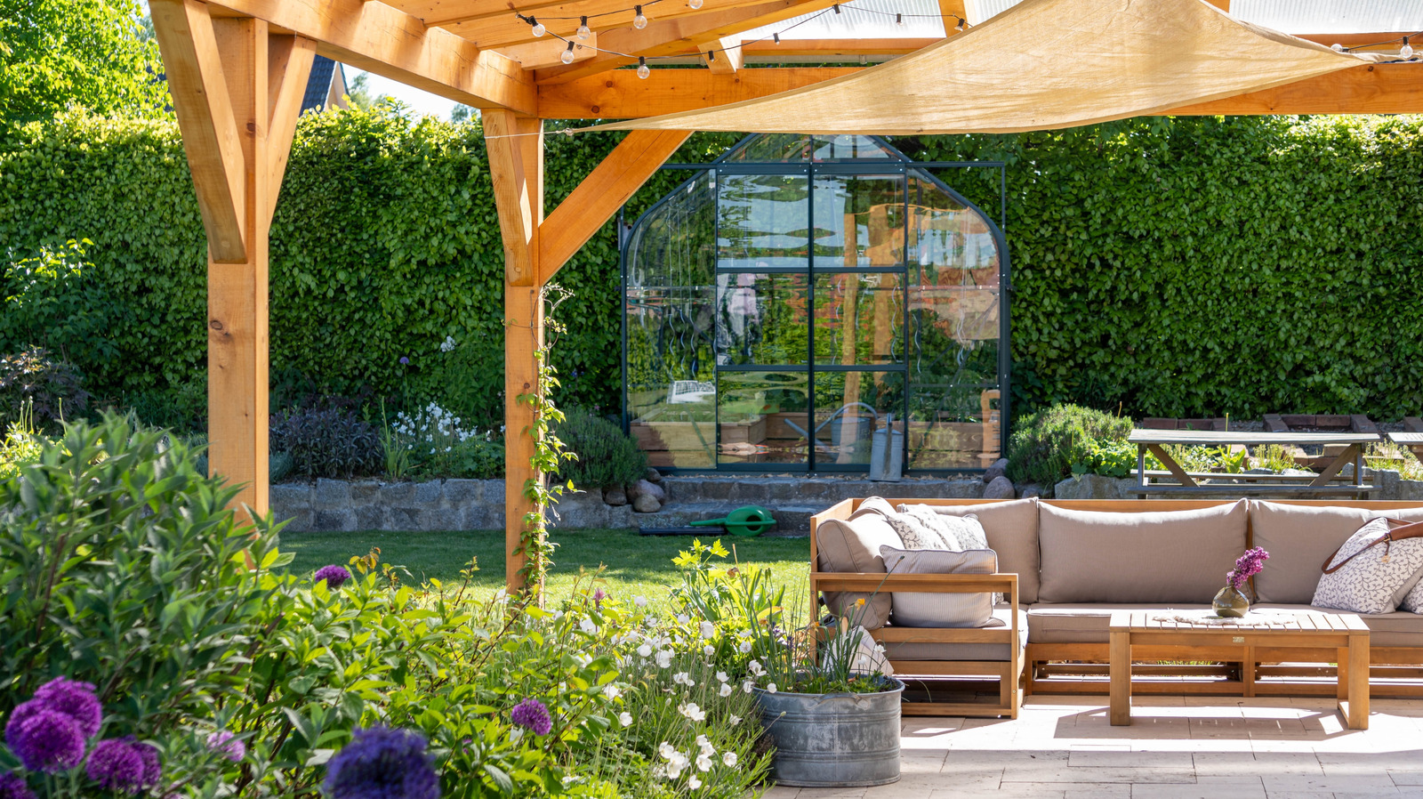 Beautiful budget-friendly outdoor living space featuring comfortable patio furniture, lush garden plants, warm string lights, decorative outdoor rug, and modern landscaping.